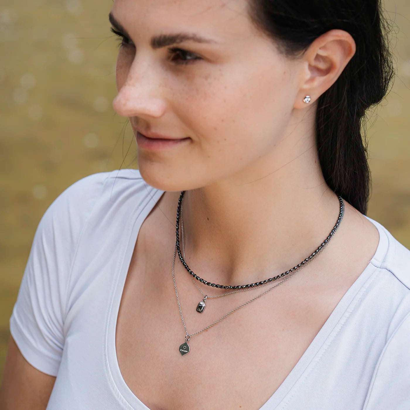 Anhaenger mit Ankerkette schwarzer Diamant 0.45ct Achteck in Platin an Modelhals bei Sonne halb nah mit schwarzer Diamantkette und Gravurplaettchen Josefine Platin weißes Oberteil