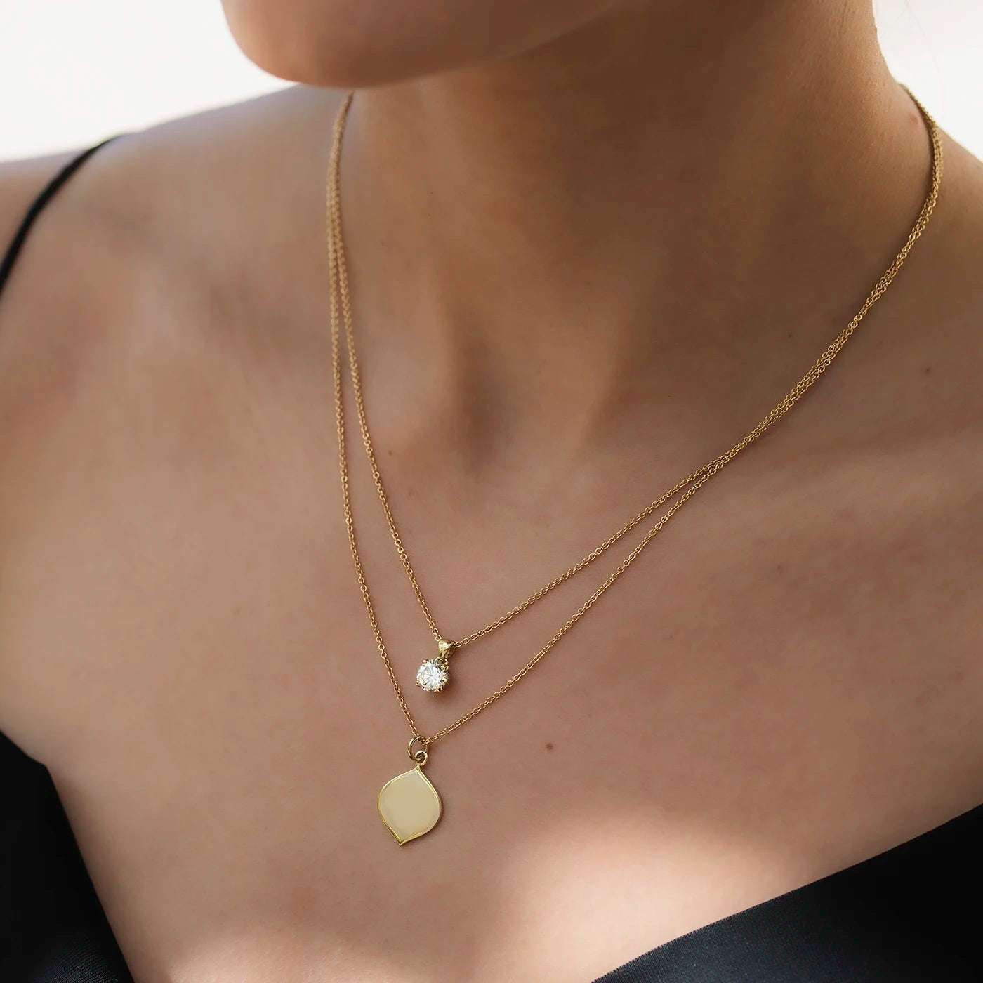 Anhaenger Petite Fleur mit 0.80ct Brillant in Gelbgold an Model draussen sehr nah mit Gravurplaettchen in Gelbgold