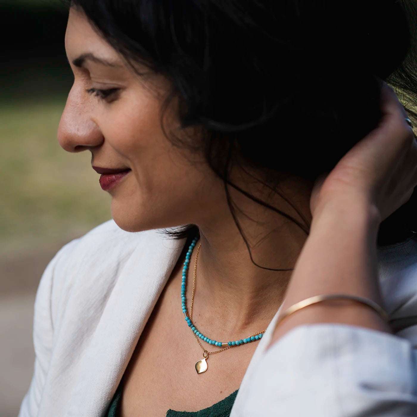 Kette Josefine Gravurplättchen in Logoform 10mm x 15mm Gelbgold an Modelhals mit gruenem Oberteil closeup profilig