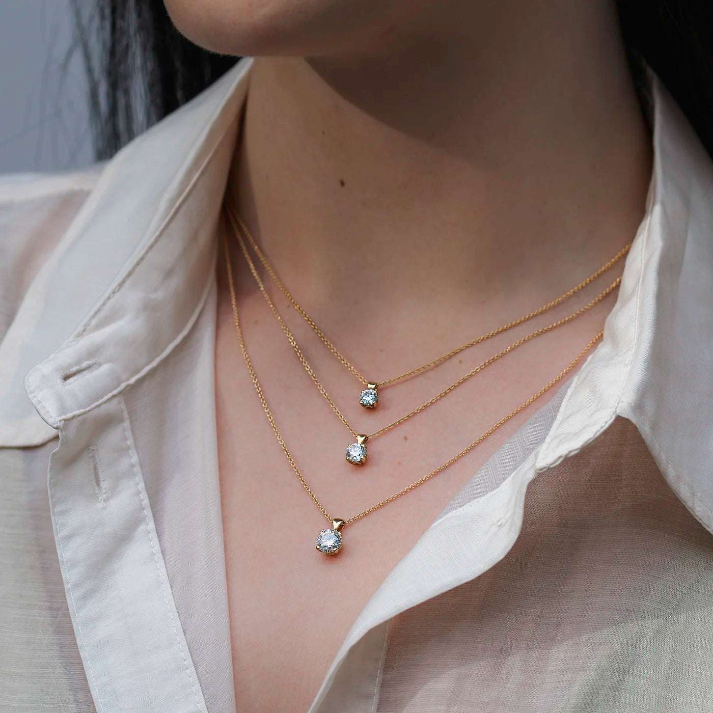 Anhaenger Petite Fleur Layering mit 0.50ct 0.80ct und 1.20ct Brillanten in Gelbgold an modelhals mit weissem Oberteil draussen closeup