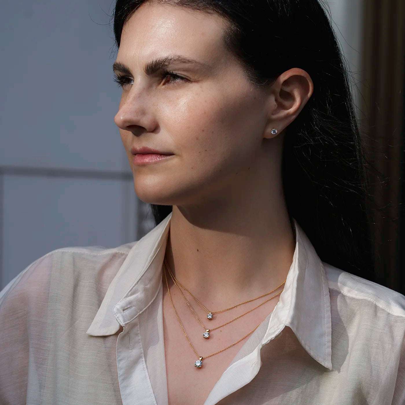 Anhaenger Petite Fleur Layering mit 0.50ct 0.80ct und 1.20ct Brillanten in Gelbgold an modelhals mit weissem Oberteil draussen Model schaut links