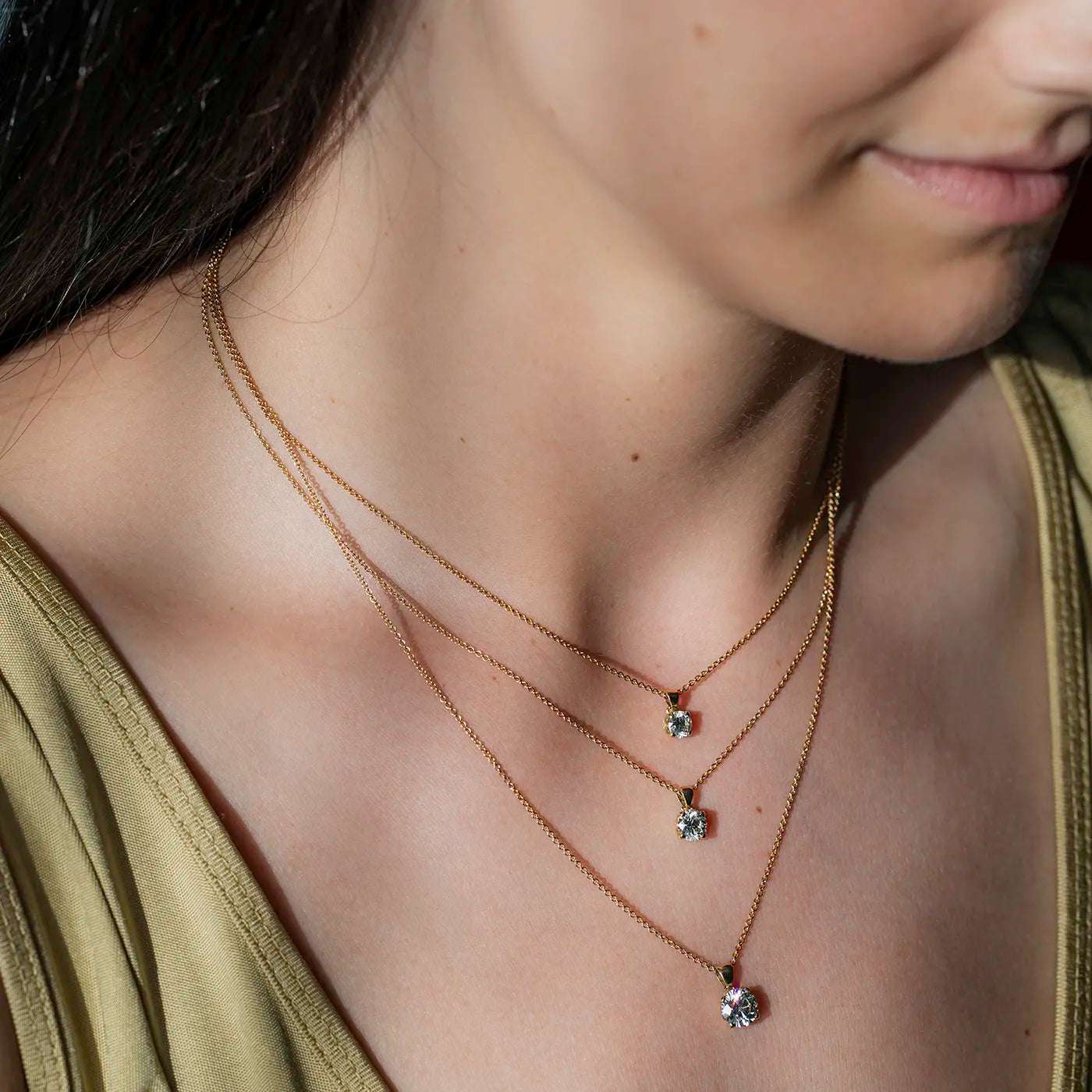 Anhaenger Petite Fleur Layering mit 0.50ct 0.80ct und 1.20ct Brillanten in Gelbgold an modelhals Closeup in Sonnenlicht Model schaut rechts