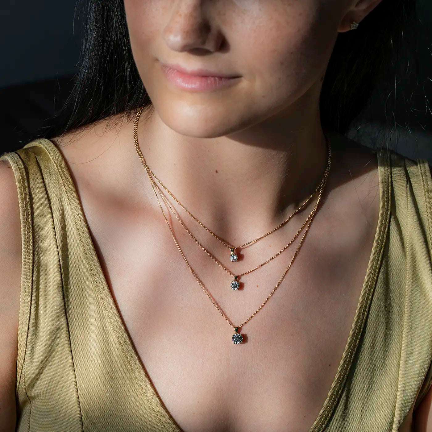 Anhaenger Petite Fleur Layering mit 0.50ct 0.80ct und 1.20ct Brillanten in Gelbgold an modelhals Closeup in Sonnenlicht Modelschaut links