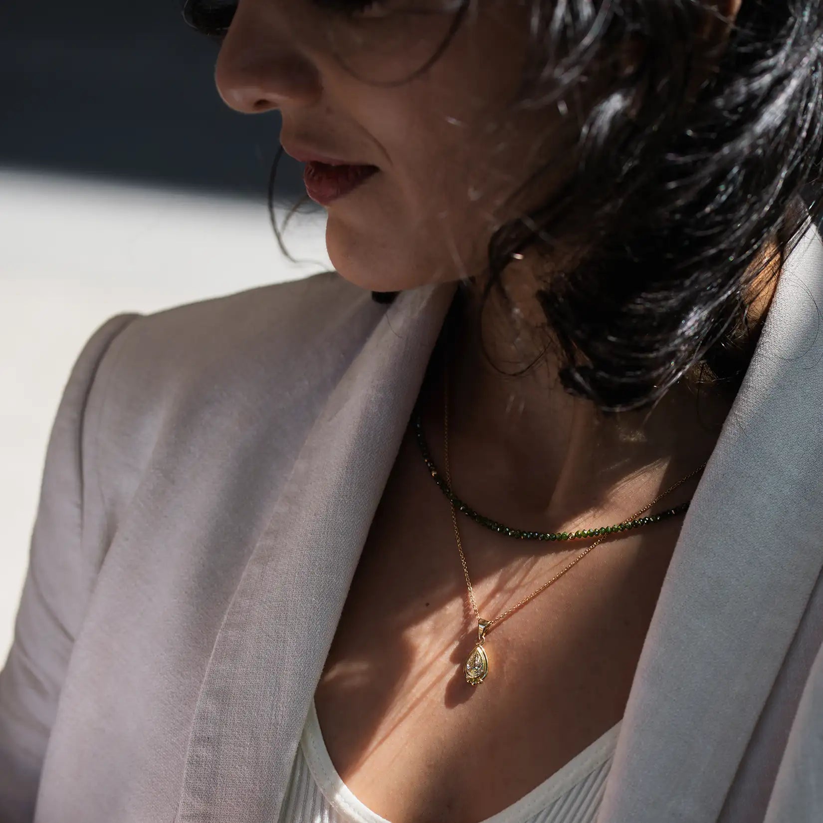 weibliches Model treagt gruene Diamantkette und grossen Diamantanhaenger in Gelbgold