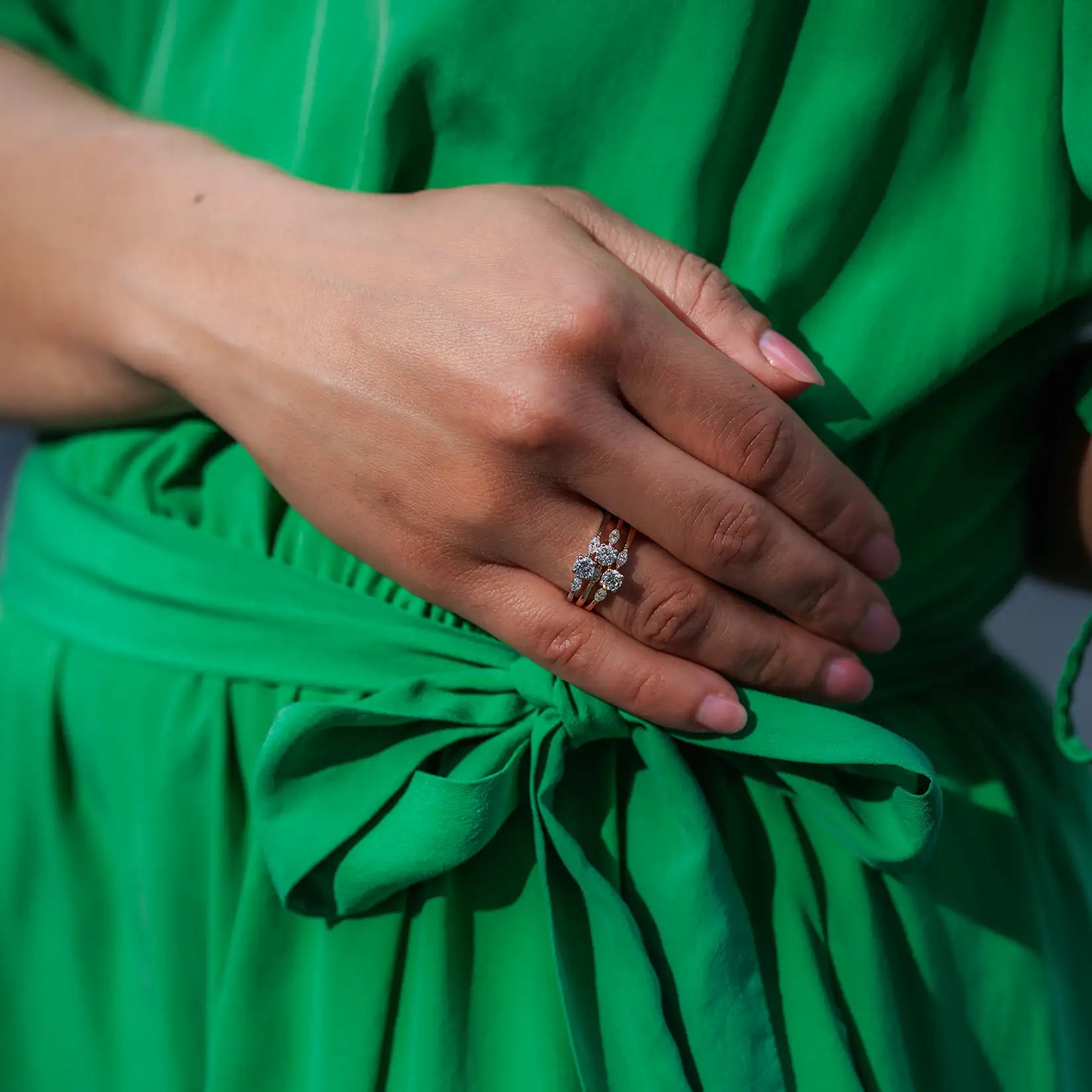 weibliches Model traegt 3 Petite Fleur Diamant Ringe auf dem Ringfinger vor gruenem Kleid
