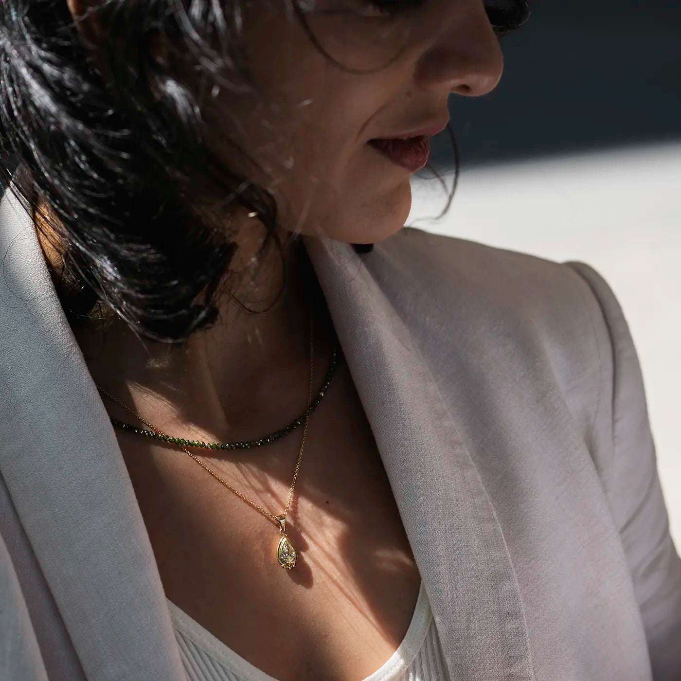 Gruene Diamantkette mit Gelbgoldelementen an modelhals nah mit Unikatkette DIamanttropfen