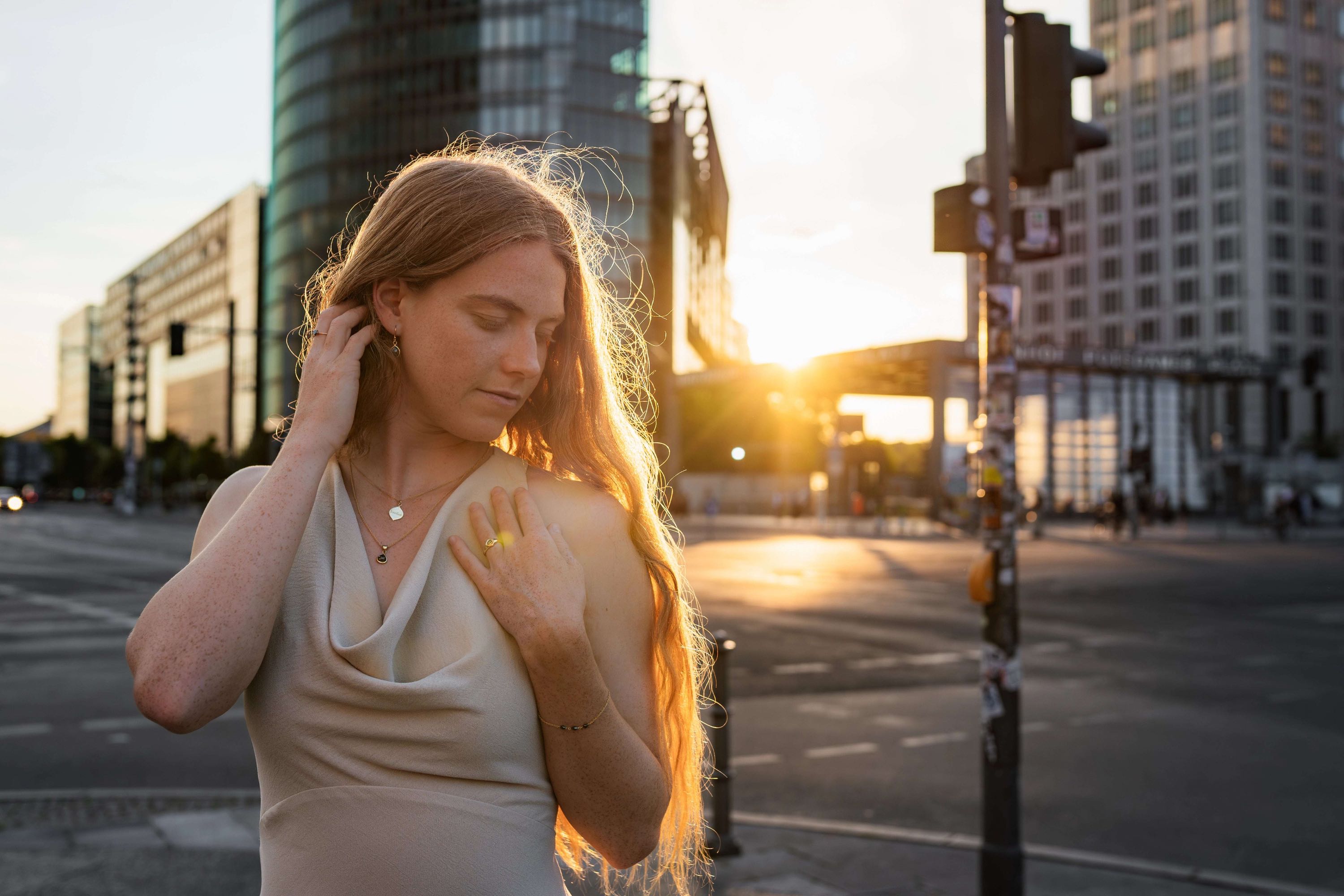 Banner Bild der Marke Josefine Model mit roten Haaren mit Josefine Halskette und anderen Schmuckstuecken vor Sonnenuntergang am Potsdamer Platz