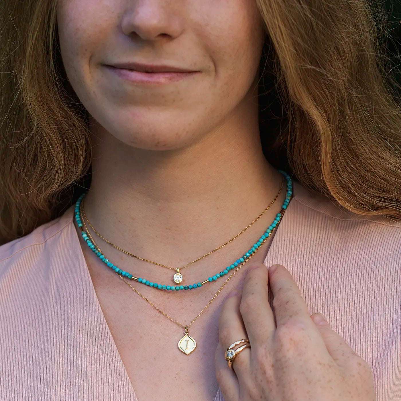 Gravurplaettchen mit 3D Initialen Gelbgold hier ein J an Modelhals frontal halbnah mit Edelsteinkette Lapis