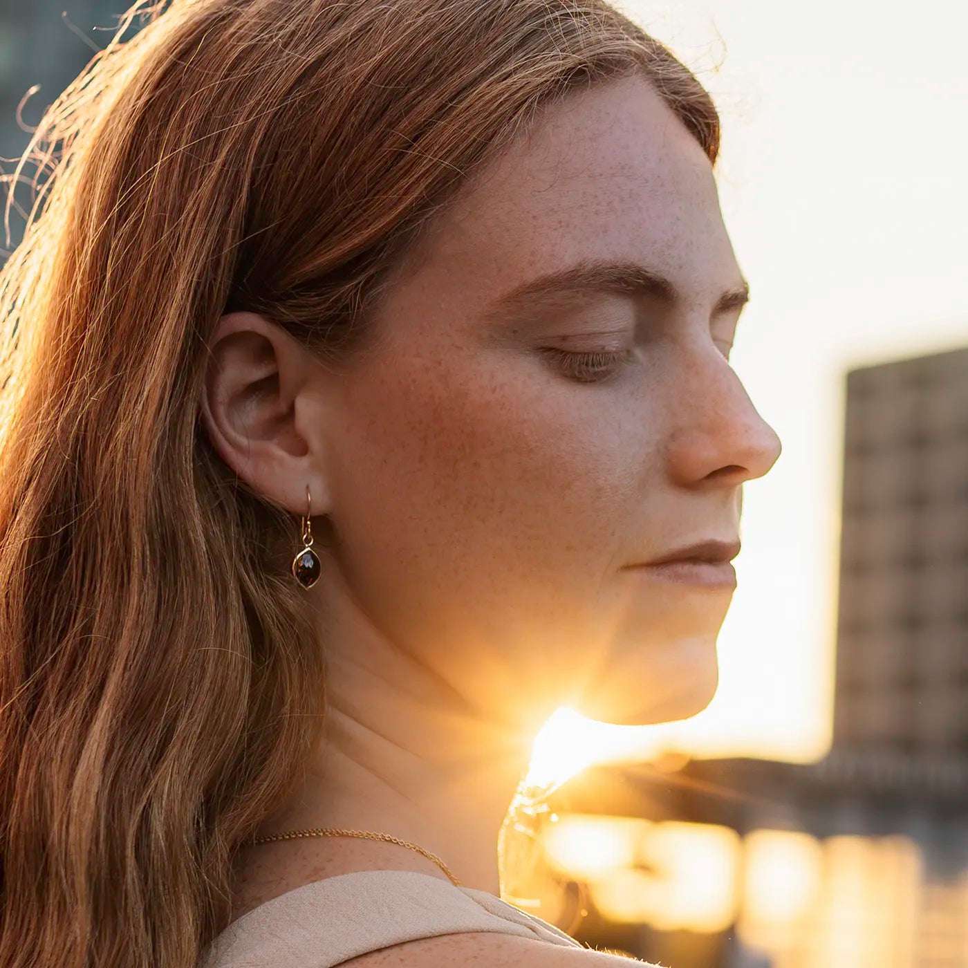 Ohrhaenger schwarzer Diamant Navette 2.0ct an Modelohr nah Sonnenuntergangslicht scheint an Kinn vorbei