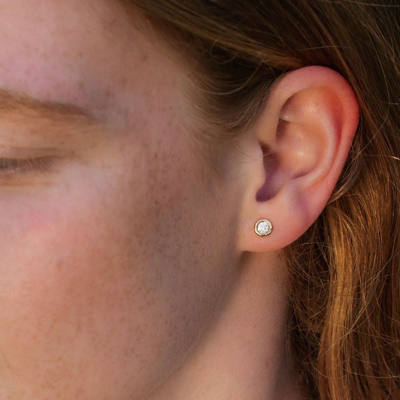 Ein Ohrstecker Balance mit einem 0,15 ct Brillanten in Gelbgold an Modelohr