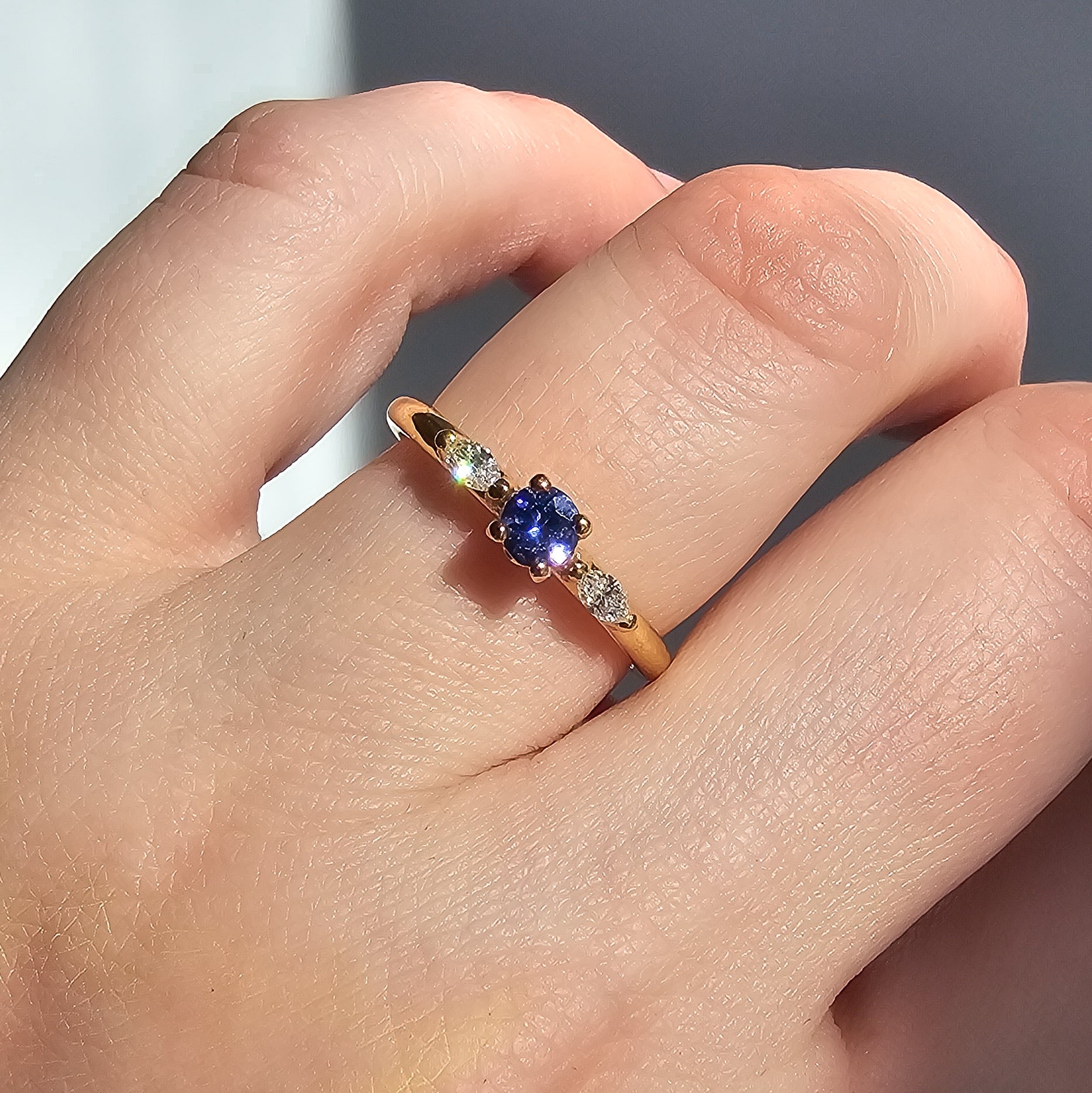 Petite Fleur Tansanit an Finger closeup mit Lichtreflex