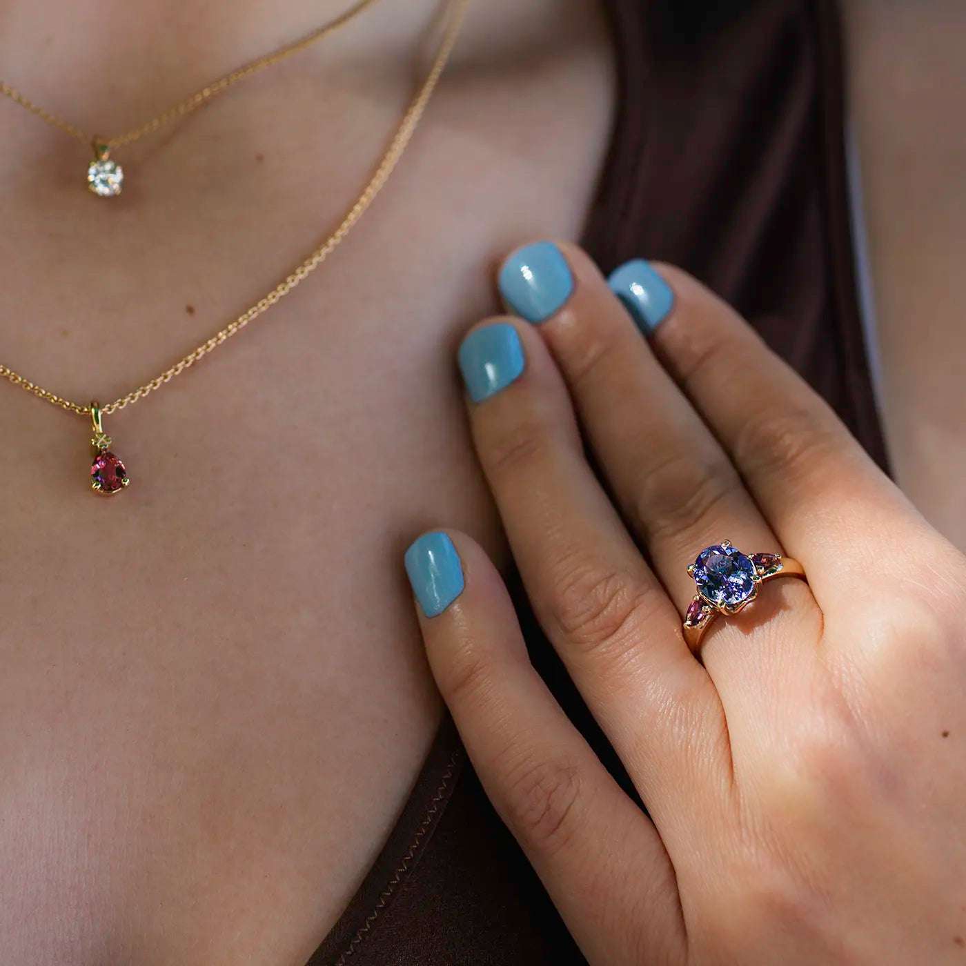 Ring Fleur Unikat blauer Tansanit und zwei magentarote Granate Rosegold im floralem Design an Modelhand auf Mittelfinger Close