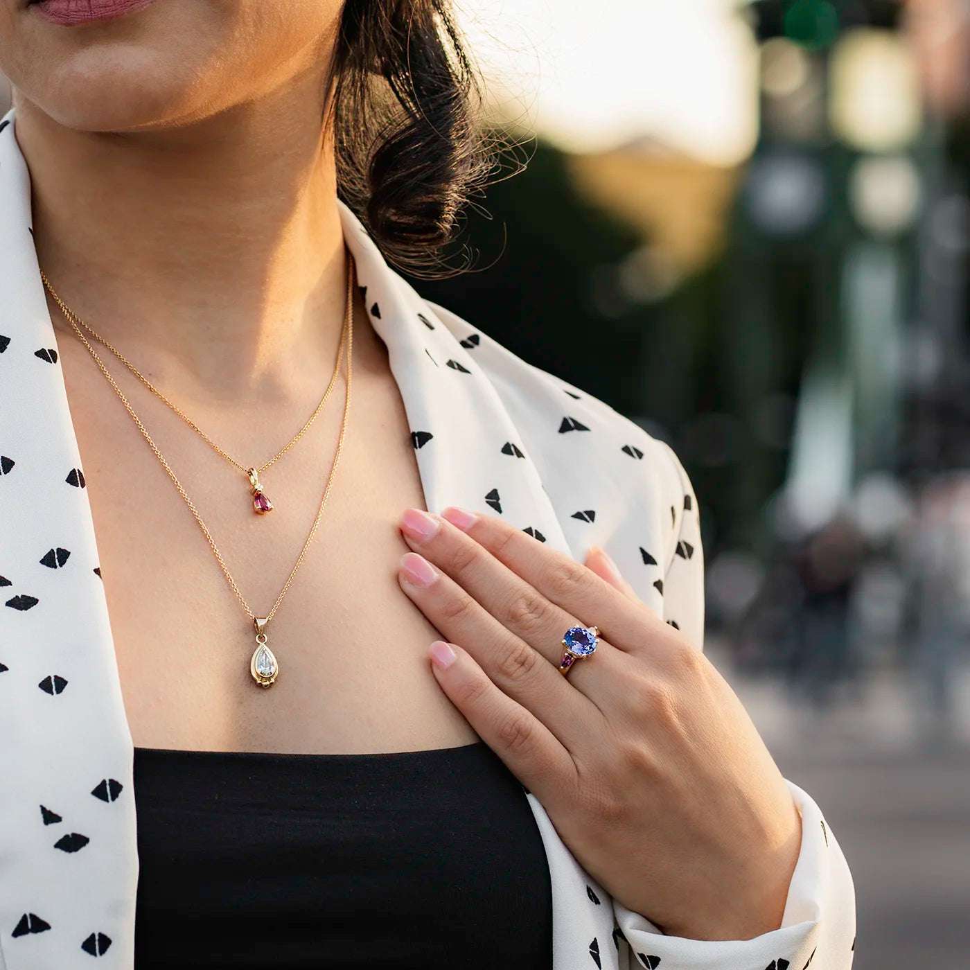 Ring Fleur Unikat blauer Tansanit und zwei magentarote Granate Rosegold im floralem Design an Modelhand auf Mittelfinger Hand auf Dekollete