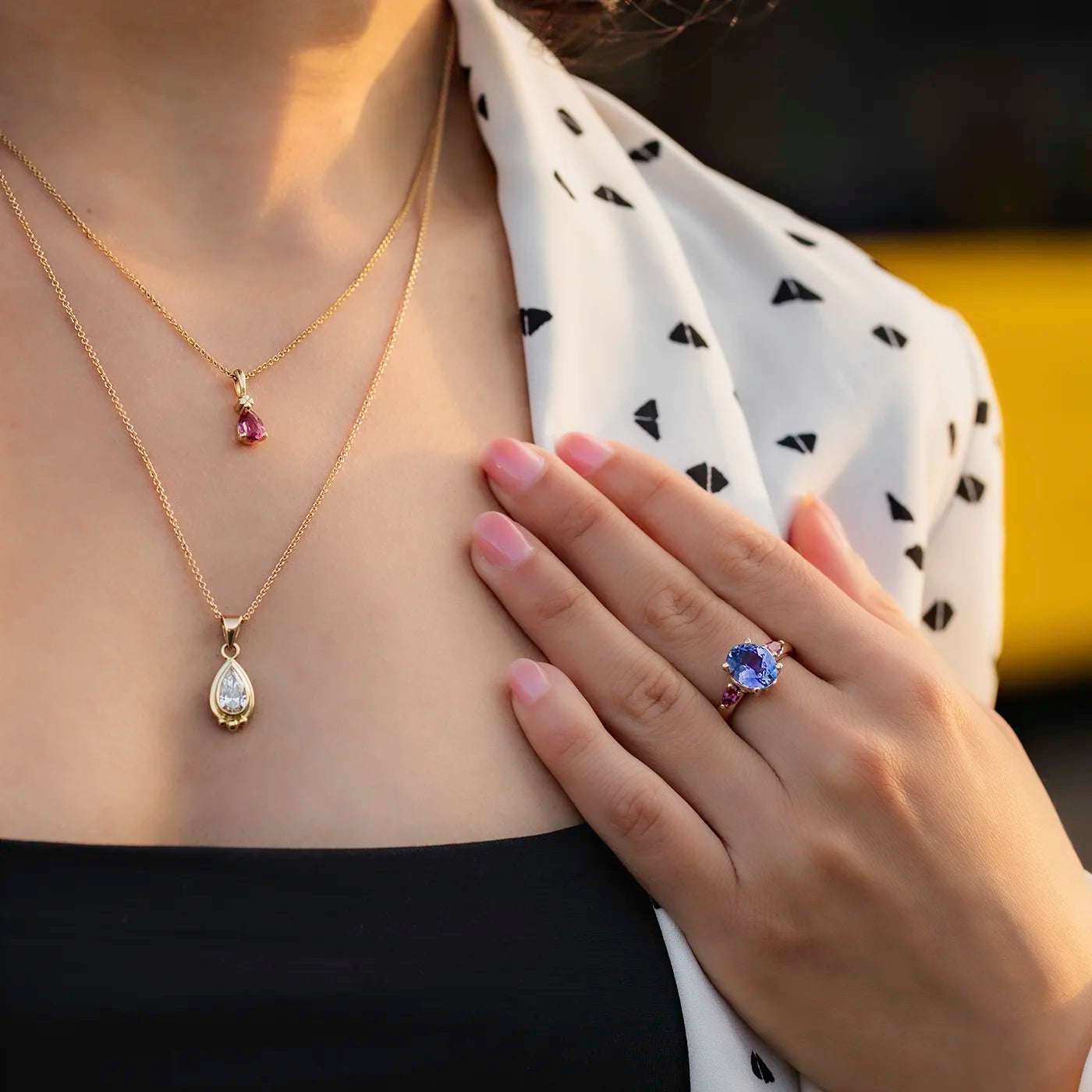 Ring Fleur Unikat blauer Tansanit und zwei magentarote Granate Rosegold im floralem Design an Modelhand auf Mittelfinger Hand auf Dekollete Closeup