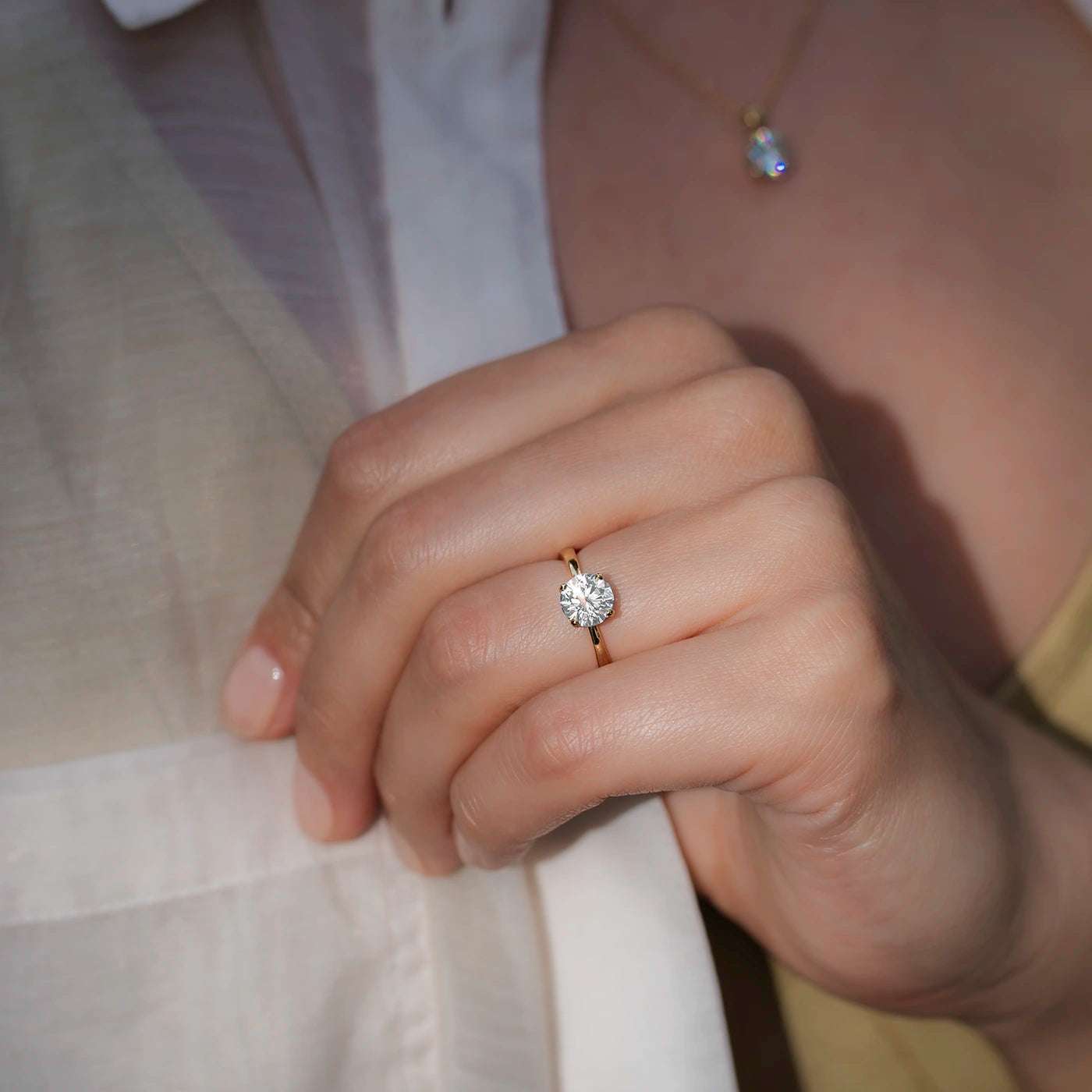 Ring Petite Fleur Solitair Gelbgold 1.50ct Brillant an RIngfinger getragen Model greift an Hemd schraeg
