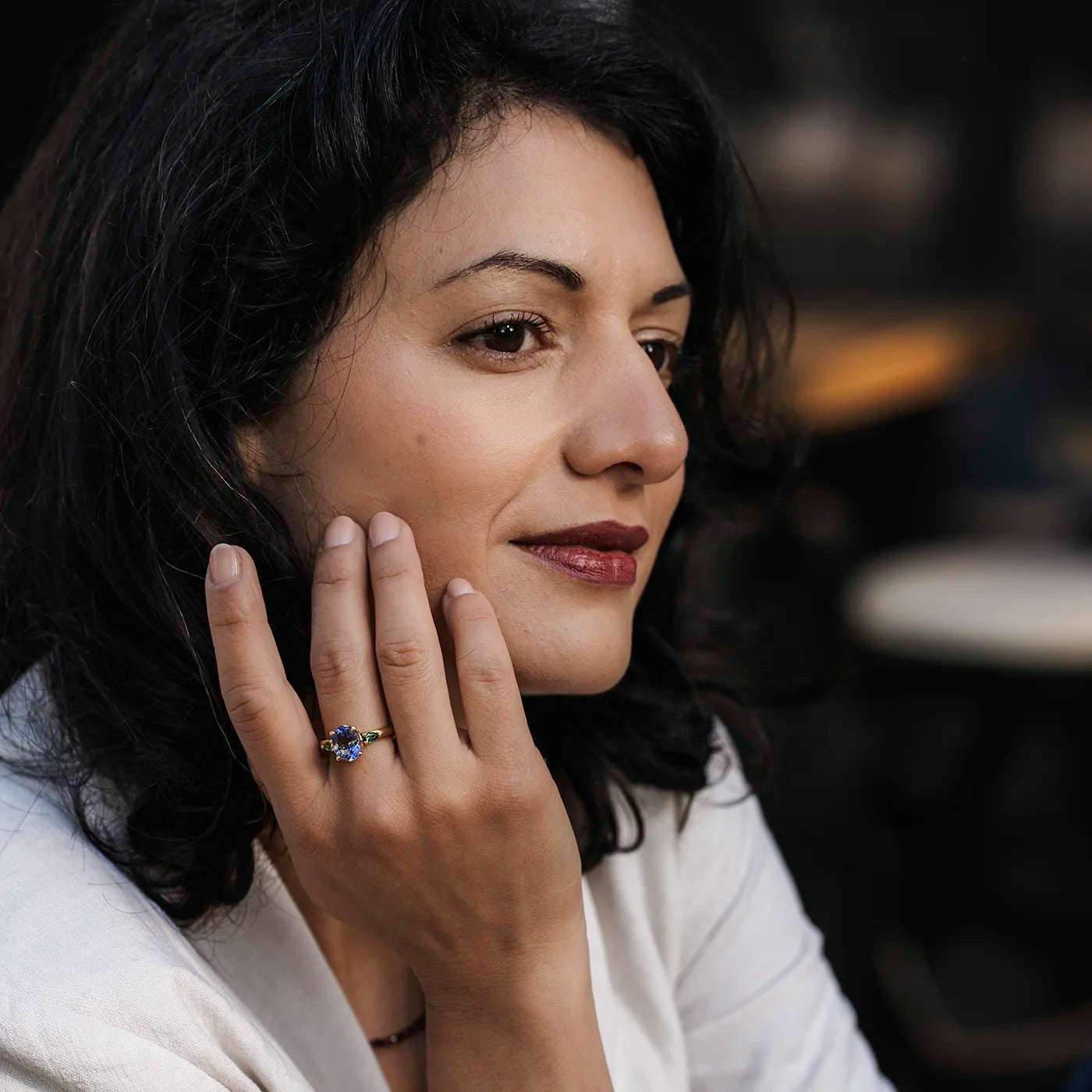 Ring Fleur Unikat blauer Tansanit und zwei gruene Turmaline Gelbgold im floralem Design an Modelhand die den Kopf stuetzt