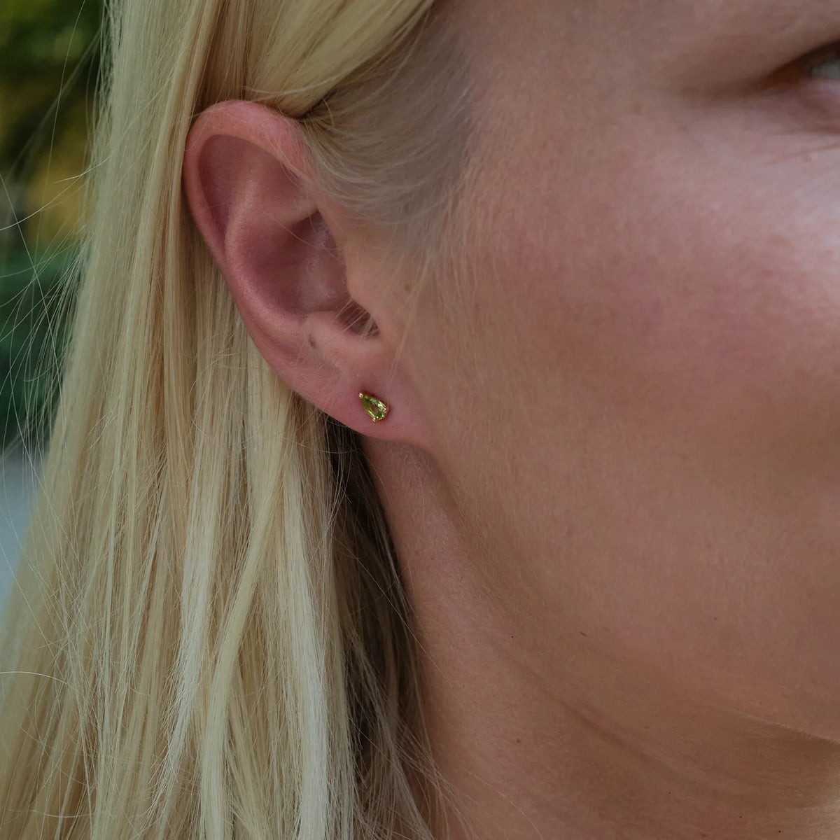 Ohrstecker Blossom grüner Peridot klein aus 925er Sterlingsilber vergoldet - am Ohr getragen, Porträt im Halbprofil