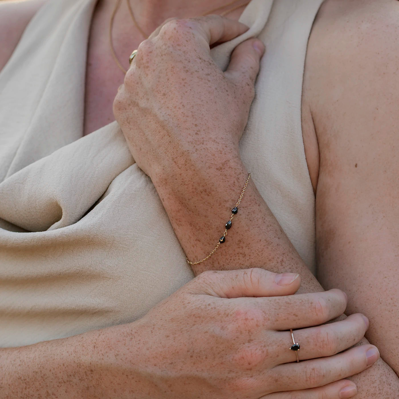 Armband aus Gelbgold mit drei schwarzen Diamanten Tropfenform an Modelarm Closeup 