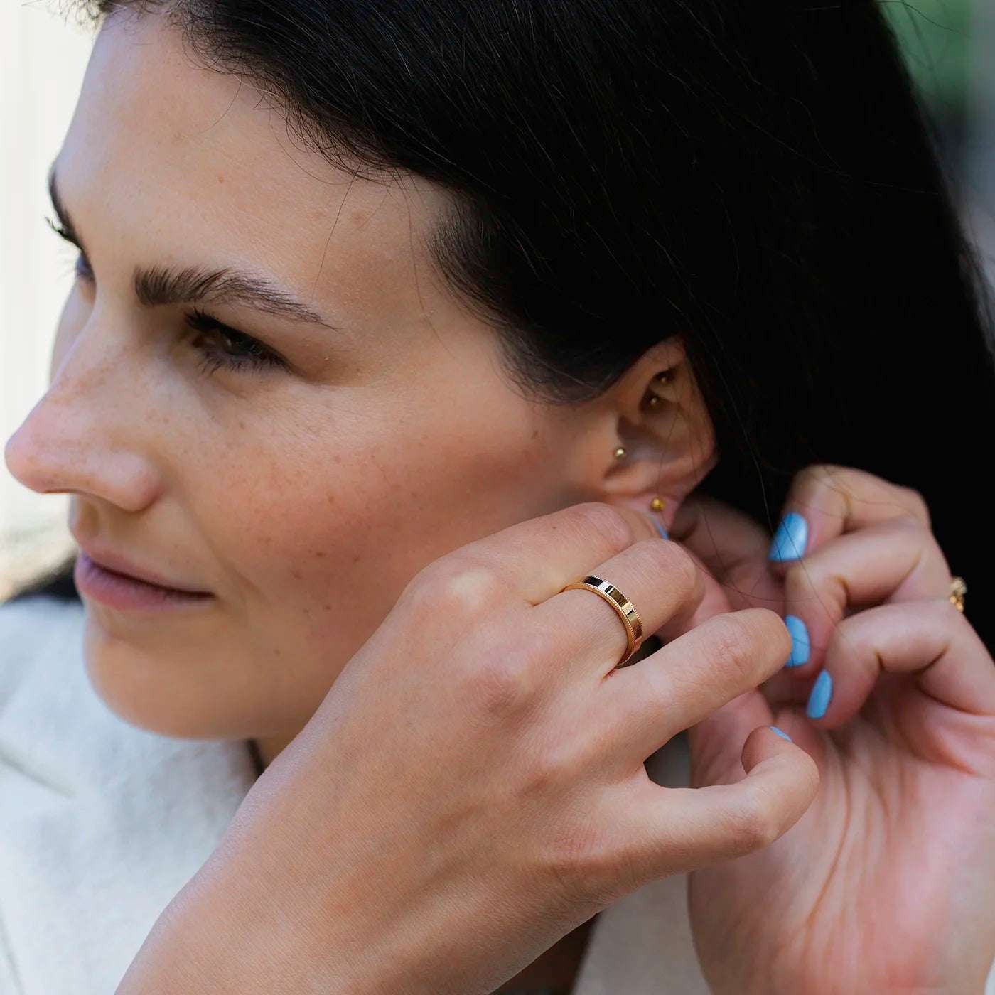 Ring Vintage Herrenring Gelbgold Ringschiene mit kleinem Kugelmuster am Rand auf beiden Seiten an einer Modelhand auf Mittelfinger closeup bei Ohrstecker anstecken
