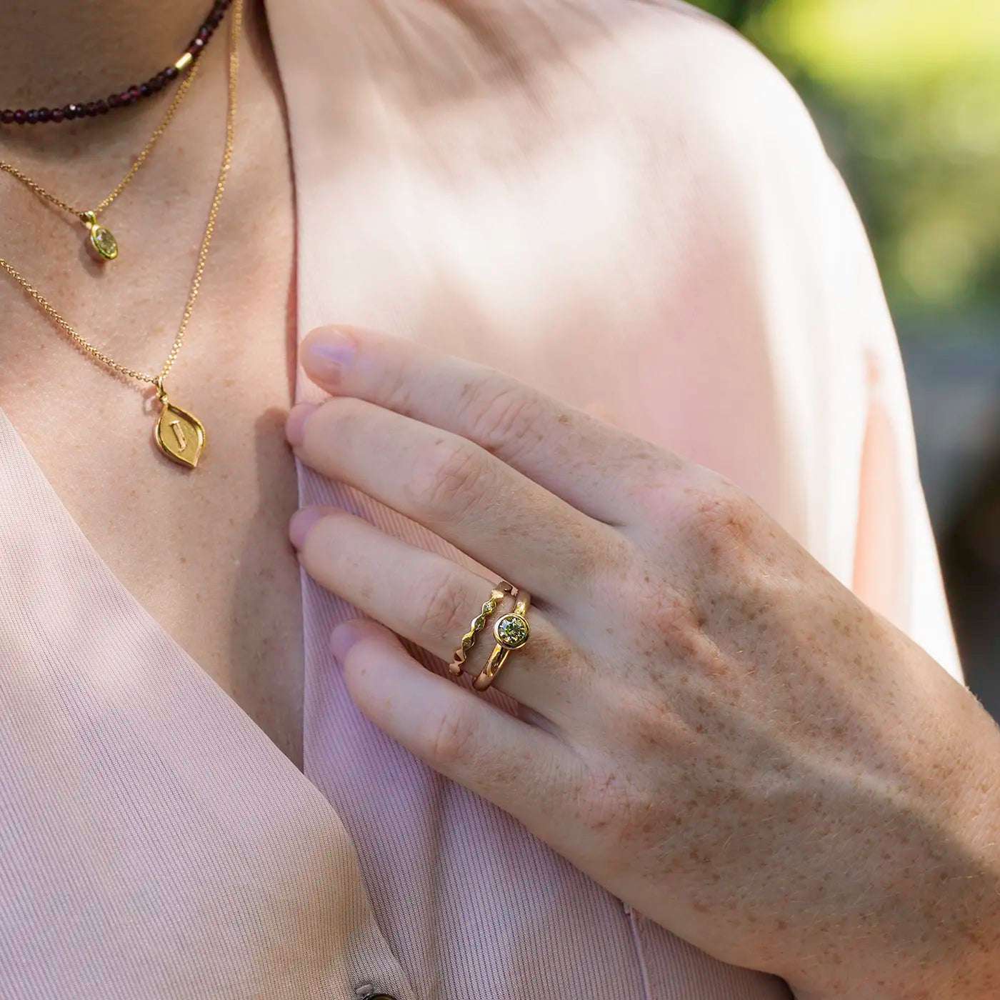 Ring Wave Rosegold die Ringschiene ist geschwungen wie Wellen Frontansicht an Modelhand Mittelfinger mit Zusteckring Balance in Rosegold Hand an Oberteil bei Dekollete