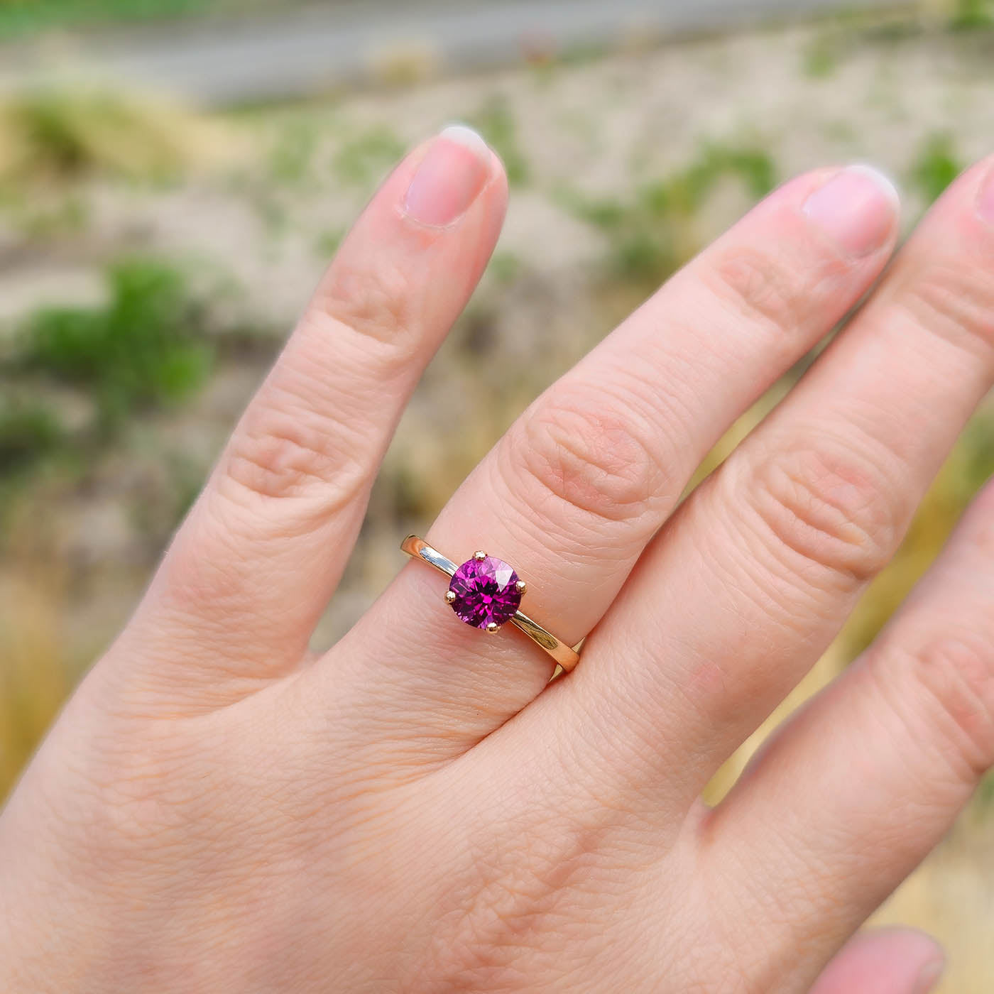 Ring Fleur Solitär Roségold mit rotem Granat getragen an Ringfinger näher dran