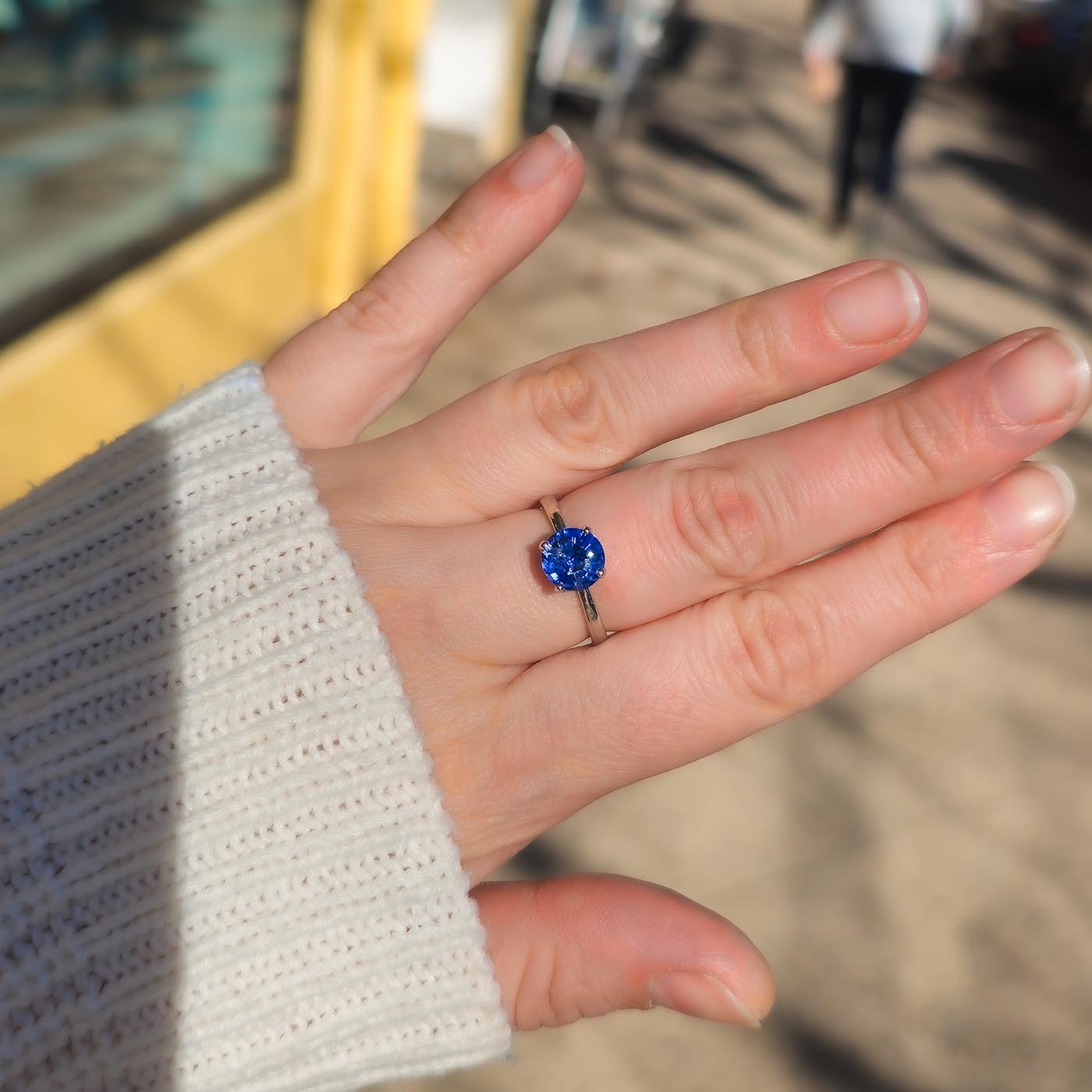Fleur Solitär blauer Saphir 950er Platin getragen an Hand in Sonnenlicht von oben