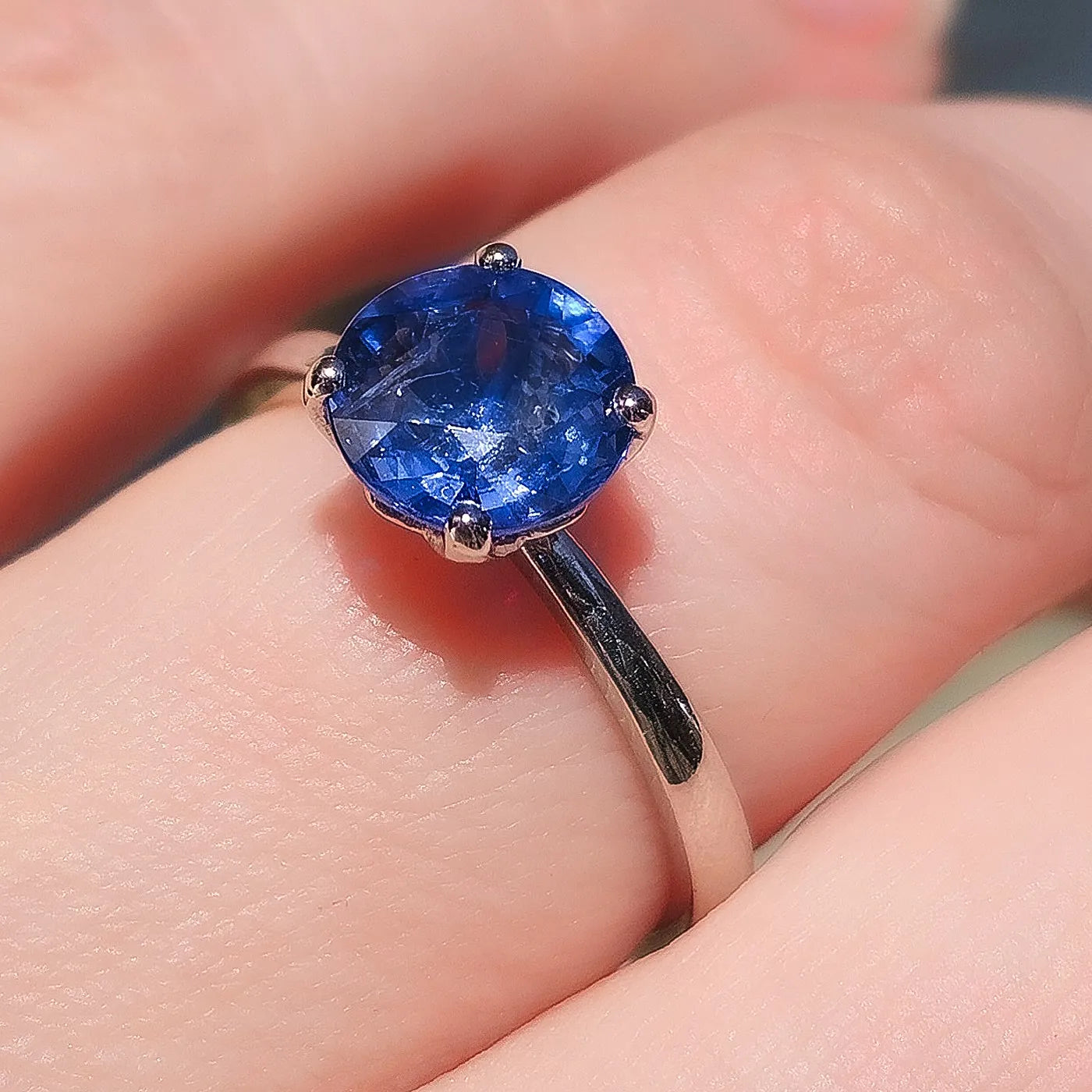 Petite Fleur Solitär Ring aus 950er Platin mit blauem Saphir in Makro-Nahaufnahme am Finger getragen