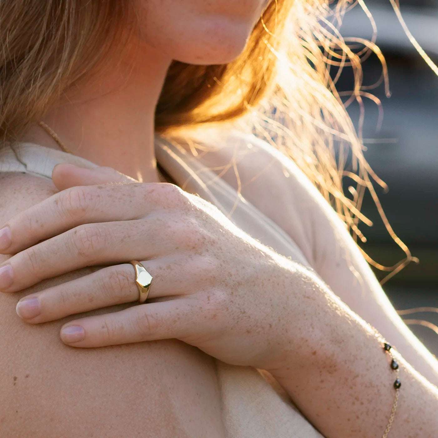 Siegelring Damen Gelbgold mit grosser Flaeche in Form Josefine Logo fuer Wunschgravur Frontansicht an Modelhand Ringfinger bei Sonnenuntergang Potsdamer Platz SuperClose