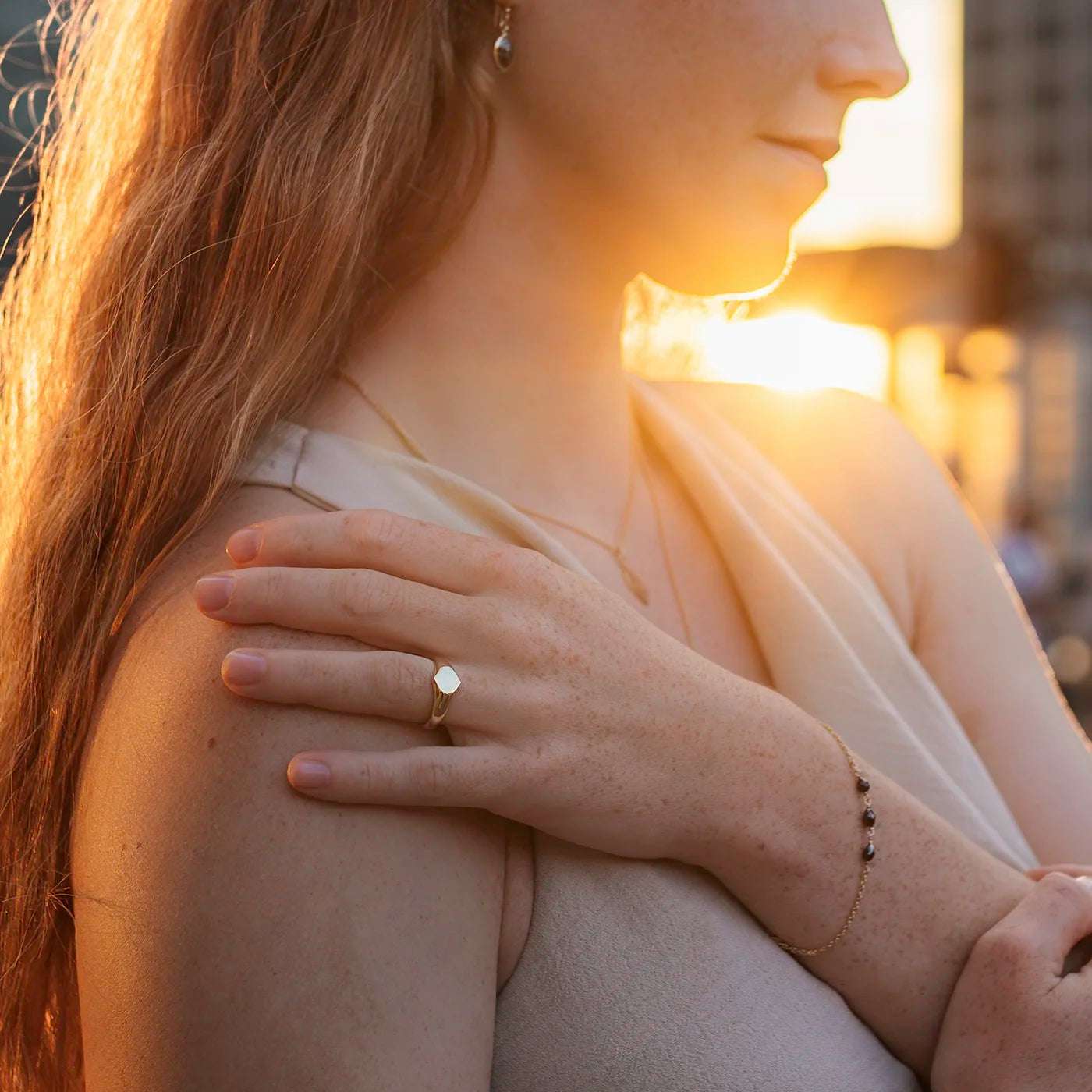 Siegelring Damen Gelbgold mit grosser Flaeche in Form Josefine Logo fuer Wunschgravur Frontansicht an Modelhand Ringfinger bei Sonnenuntergang Potsdamer Platz Close