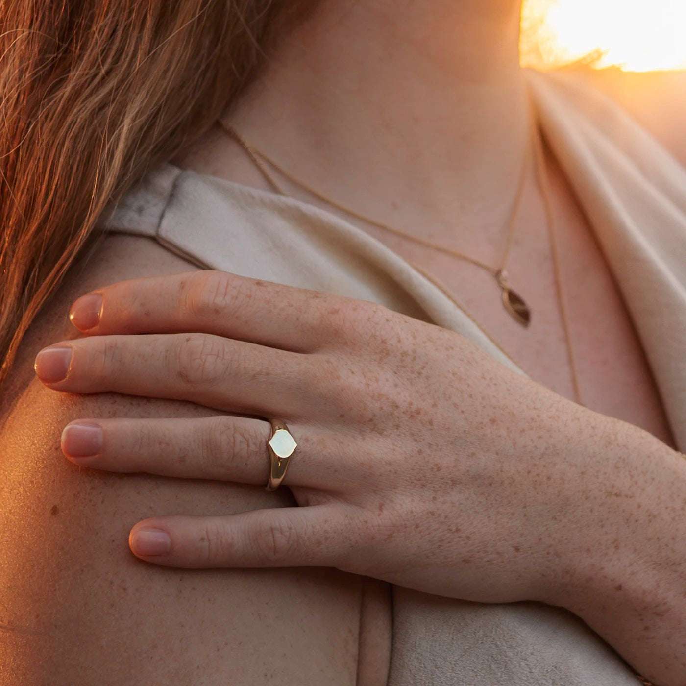 Siegelring Damen Gelbgold mit grosser Flaeche in Form Josefine Logo fuer Wunschgravur Frontansicht an Modelhand Ringfinger bei Sonnenuntergang Potsdamer Platz Close anderer Lichteinfall