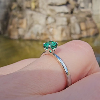 Petite Fleur Solitär Ring aus 950er Platin mit grünem Smaragd am Finger getragen vor Brunnen in Berlin Wilmersdorf